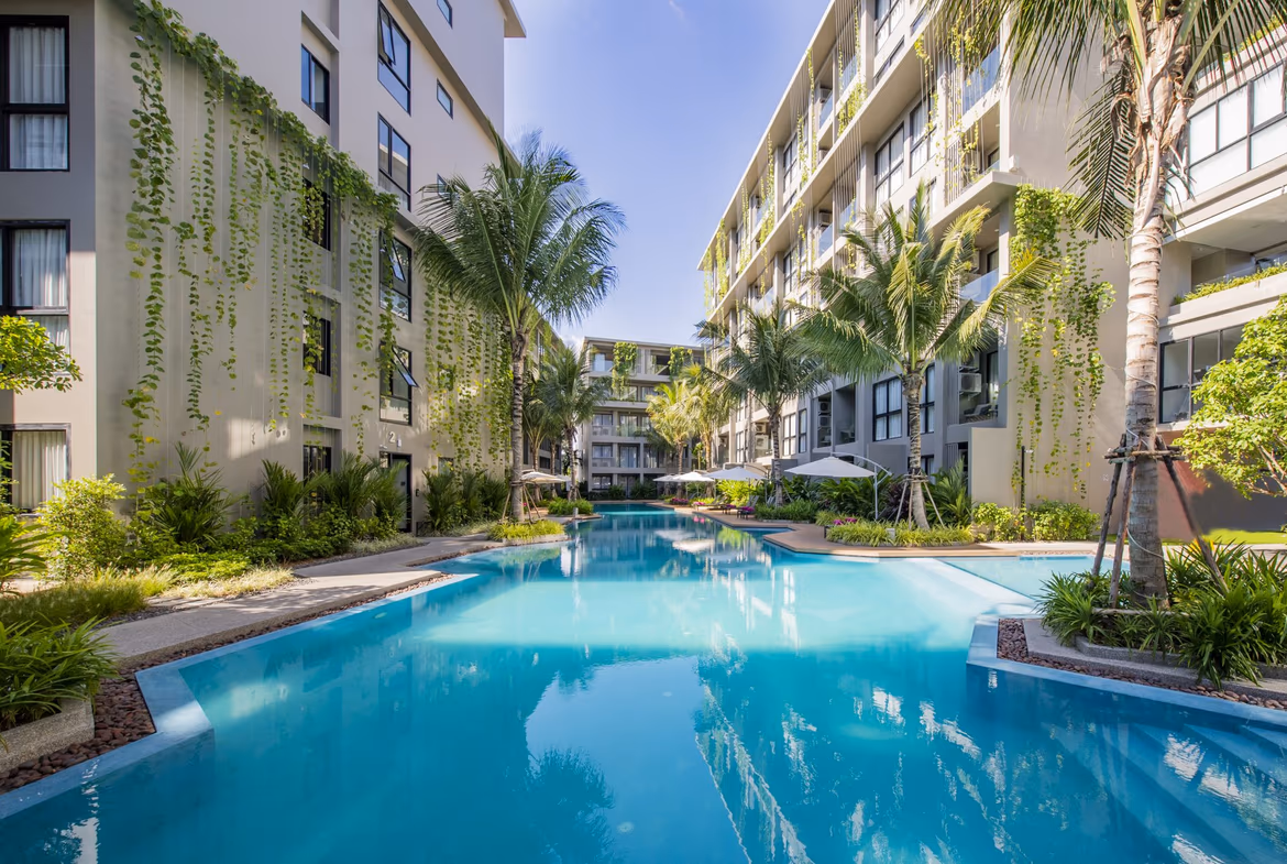 A modern condominium building in Bang Tao with multiple balconies and large windows on a sunny day.