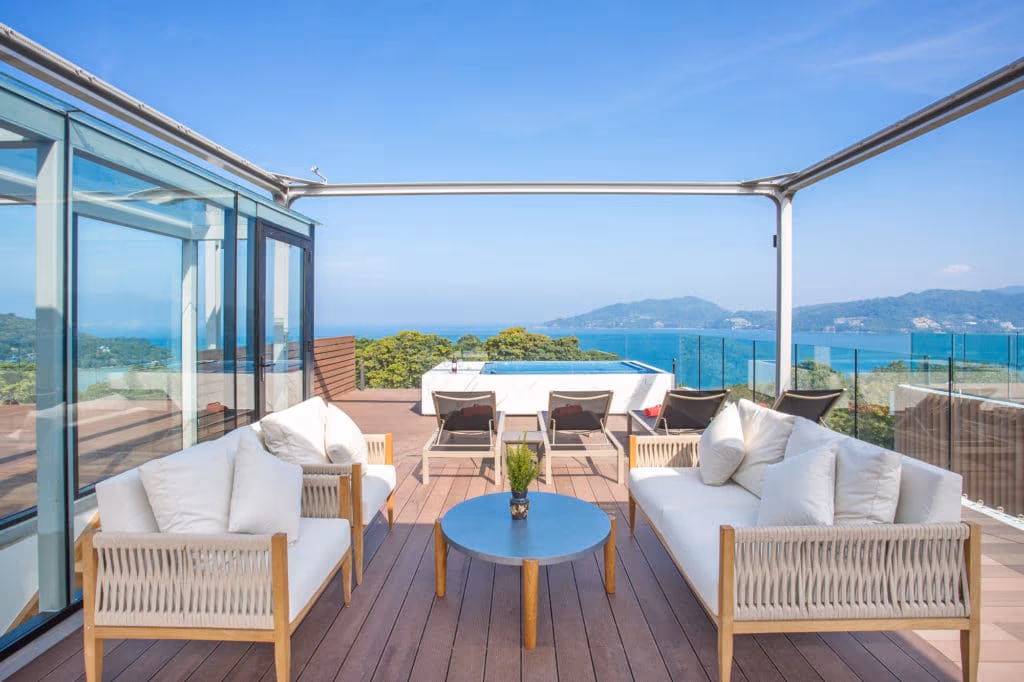 An ocean view from a balcony overlooking a bay with hills and buildings.