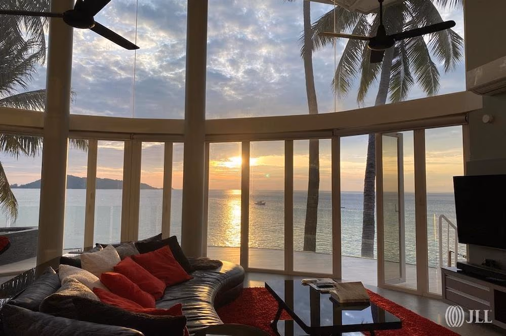 An outdoor patio with a seating area overlooks a swimming pool and the ocean.