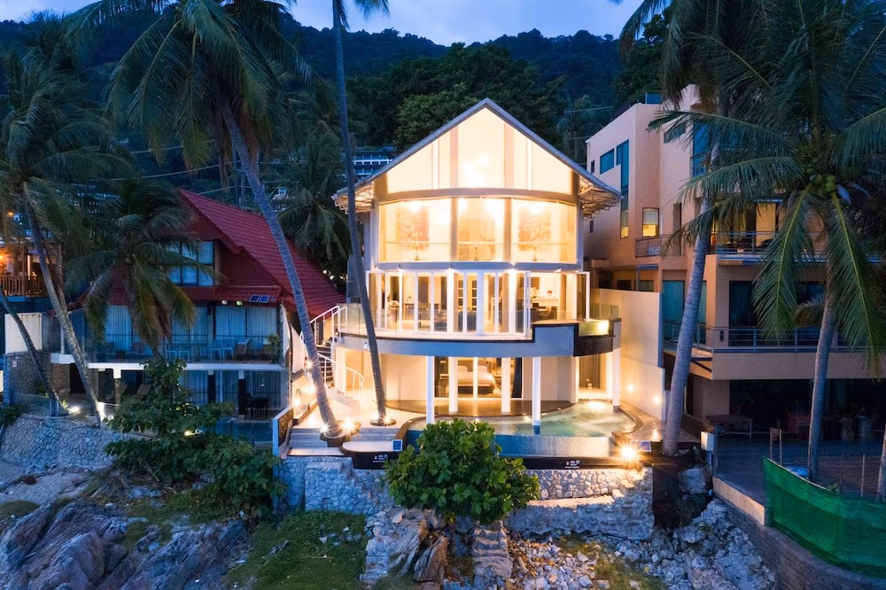 The room features a large window offering a panoramic view of the sea and coastline.
