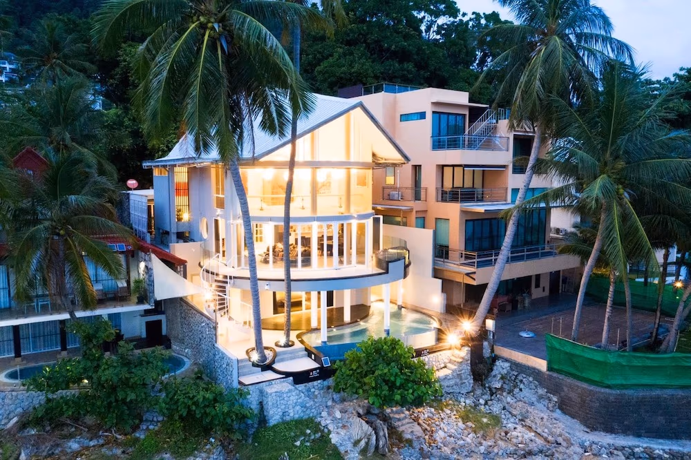 This is a modern, three-bedroom villa in Patong with a unique beachfront design. The property features large windows and a clean, contemporary exterior directly facing the ocean.