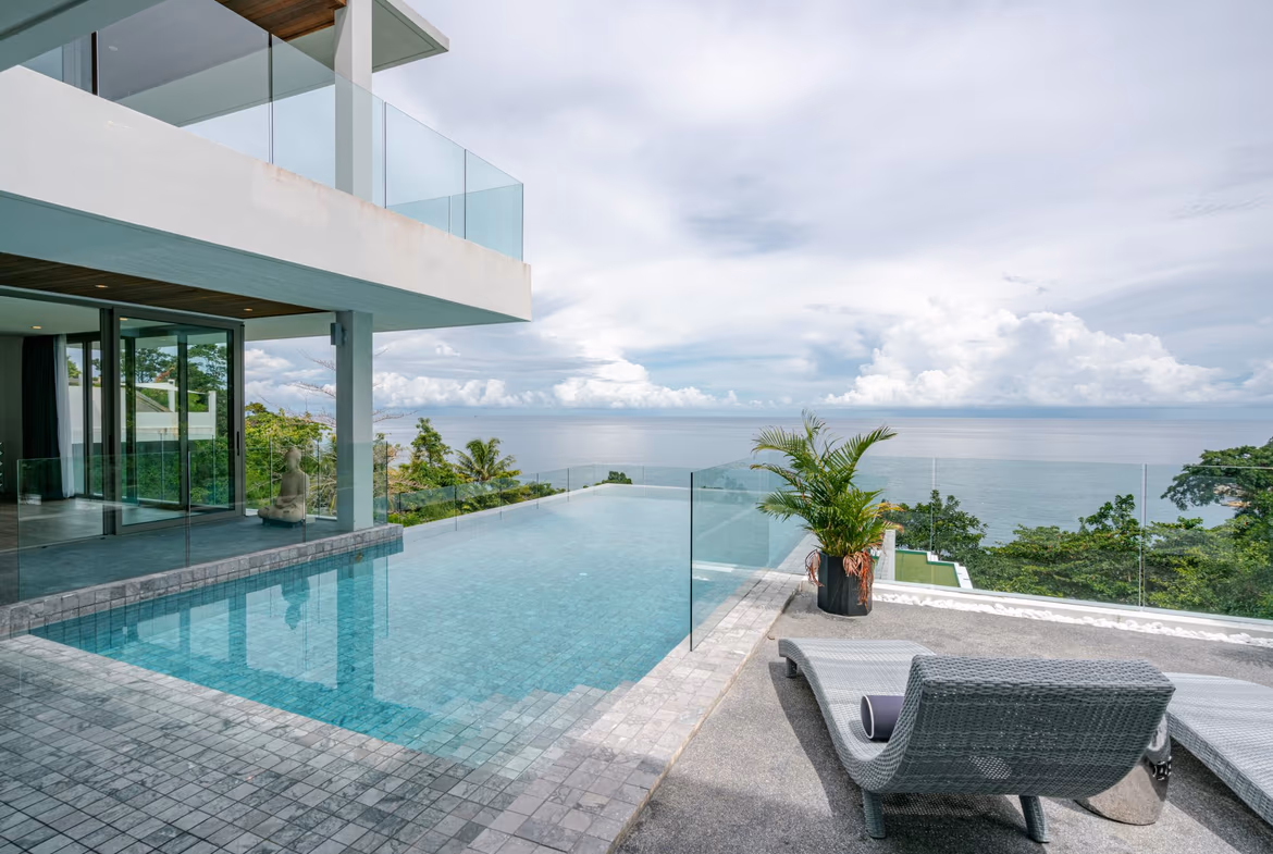 A multi-story contemporary villa with dark roofs and glass balconies overlooking the ocean. The six-bedroom property is located in Kamala.