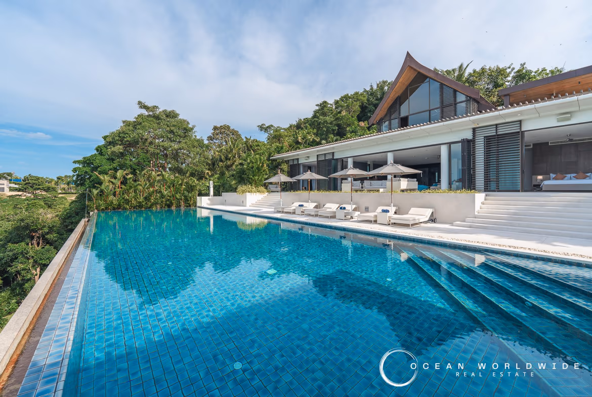 An infinity pool overlooking the ocean with palm trees on either side.