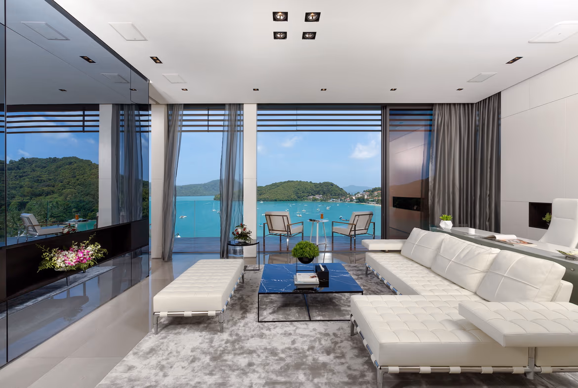 A panoramic outdoor view showcases an infinity pool overlooking the ocean, framed by lush tropical vegetation.
