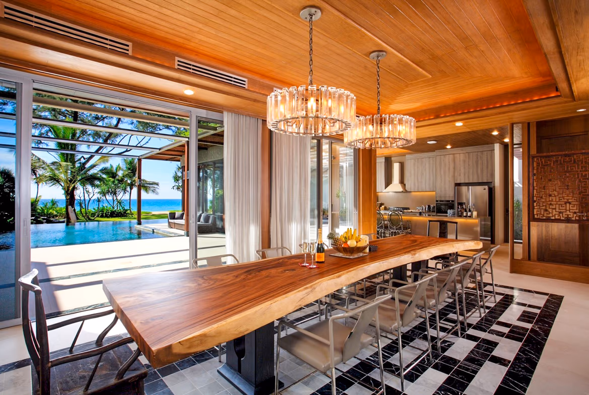 An interior view of a room with a large, comfortable bed and a private balcony overlooking the ocean.