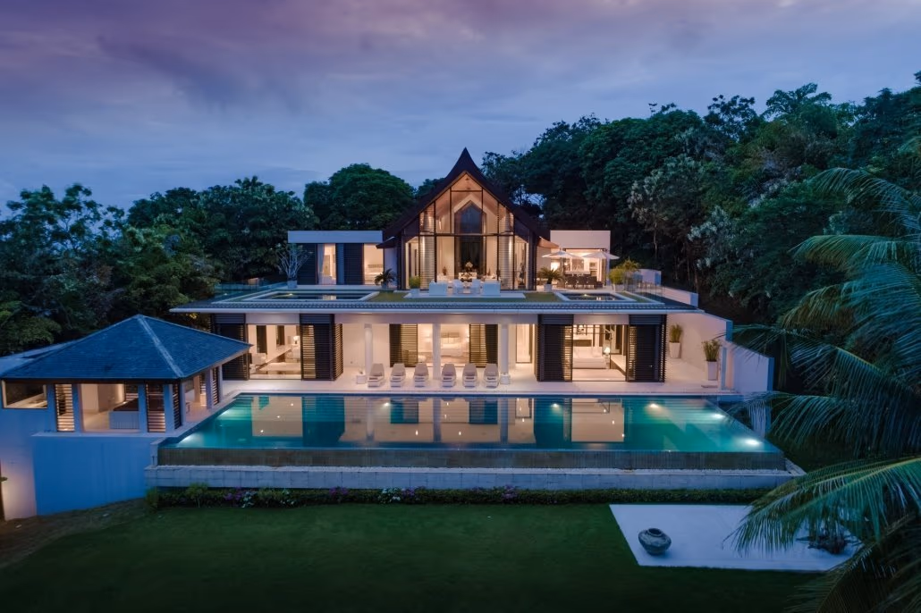 An infinity pool overlooks a palm-fringed beach and the ocean beyond.
