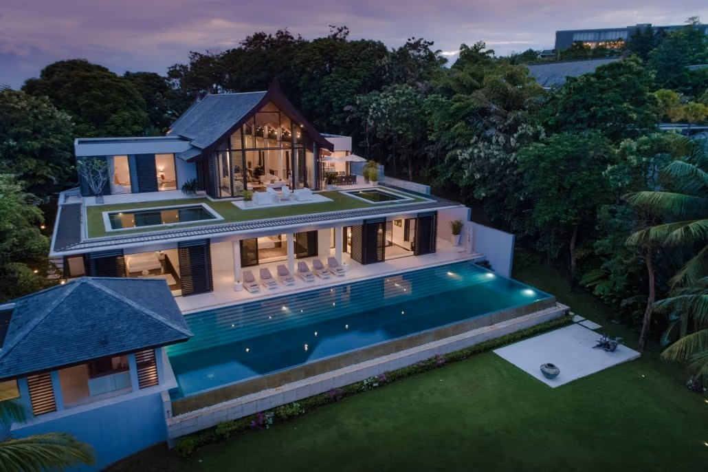 The photo shows a spacious living room with large windows overlooking a beachfront.