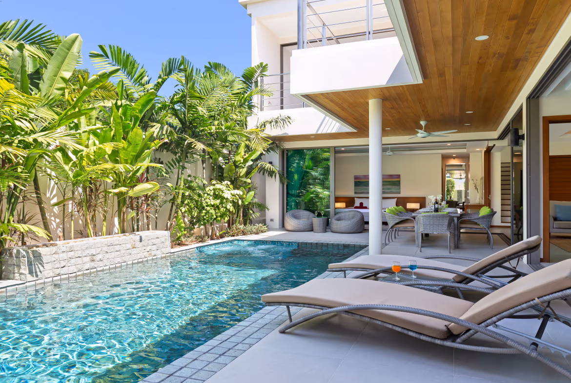 A modern living area with a sofa and glass doors opening to an outdoor space.