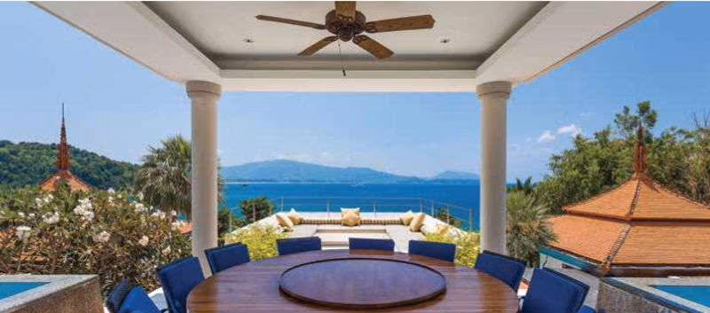 An infinity pool extends toward the ocean, flanked by lounges and verdant landscaping.