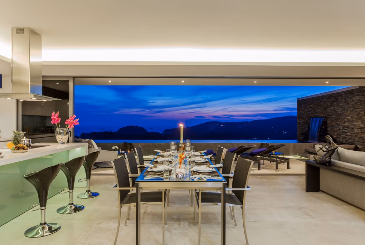 Open-plan dining room at dusk with a panoramic sea view, Layan