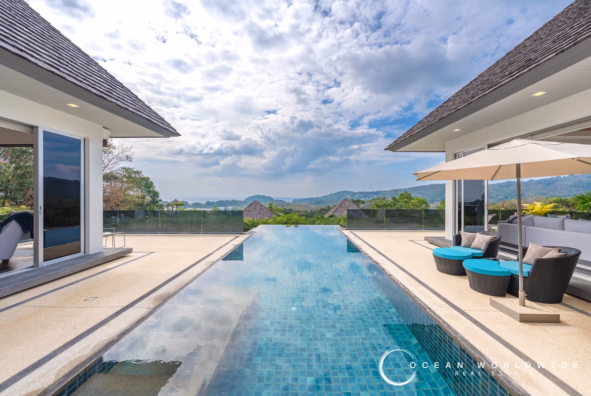 Five-bedroom hillside villa in Layan with ocean views. Modern architecture with a large infinity pool overlooks a tropical landscape.