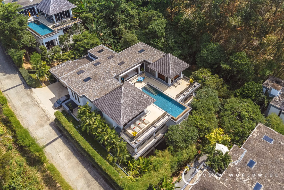 An infinity pool overlooks the ocean and a lush hillside.