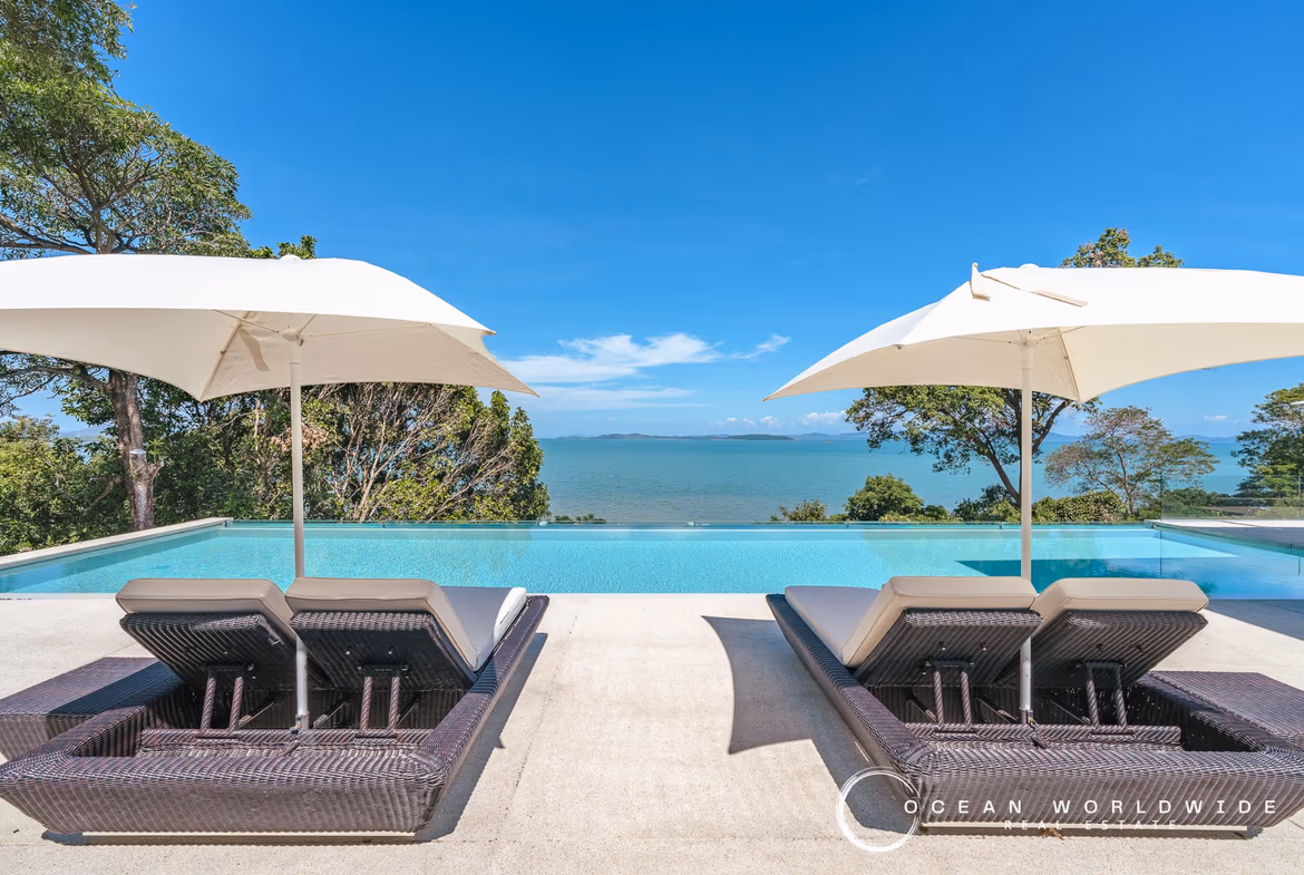 A modern, multi-story waterfront villa in Cape Yamu features an infinity pool overlooking the ocean. The property has four bedrooms.