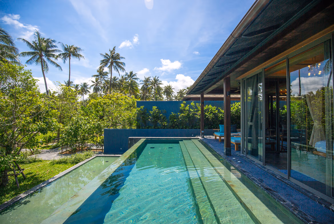 A two-bedroom villa in Natai with direct beach access. The exterior features a thatched roof and a private plunge pool.