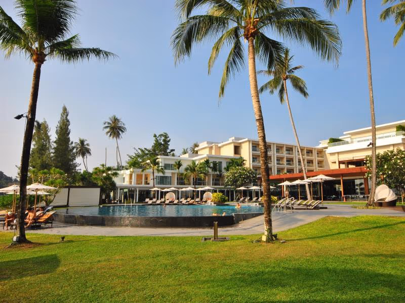 An infinity pool overlooks a serene bay with boats and lush green hills.