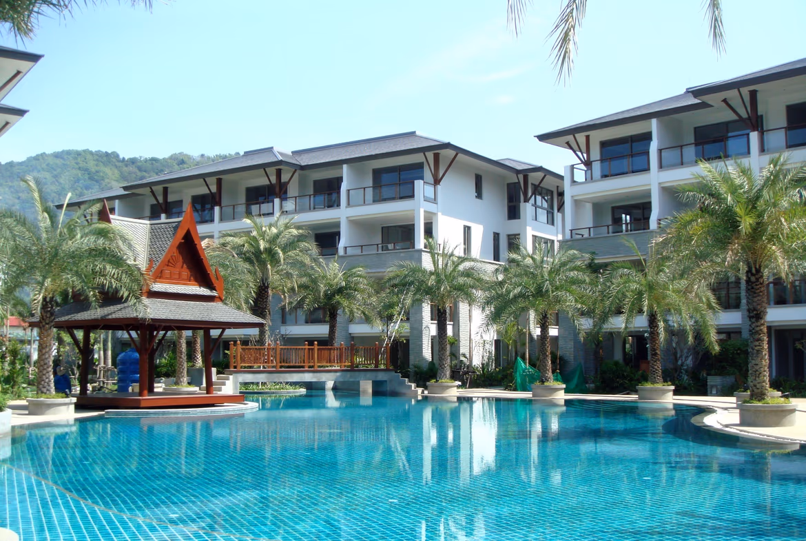 Exterior front view of a four-bedroom luxury duplex penthouse condominium in Naithon, featuring a prominent balcony overlooking the ocean. The modern building includes large windows and a clean facade.