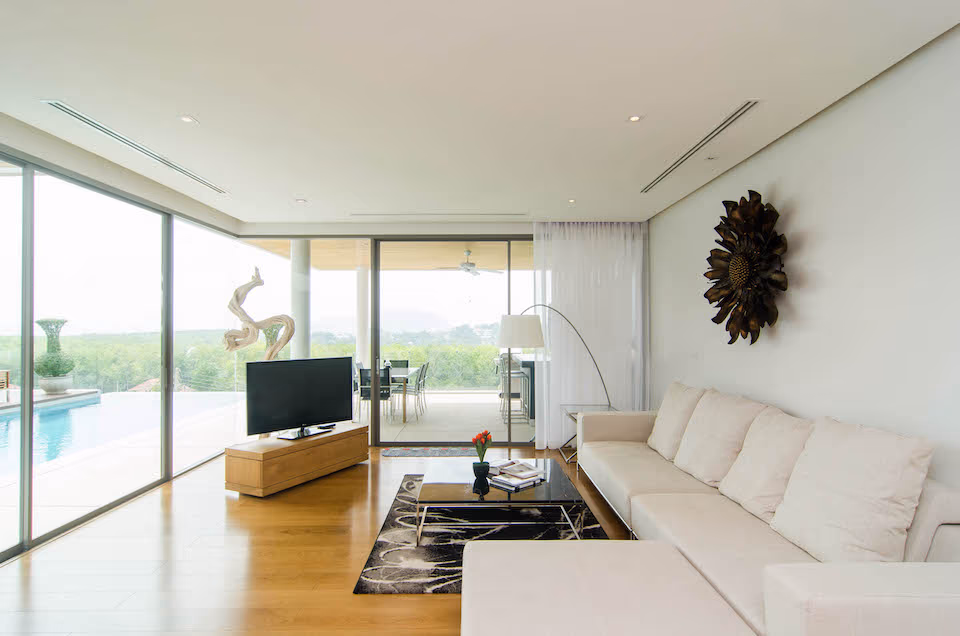 A modern living room with a large sofa, coffee table, and area rug, featuring an abstract painting on the wall.