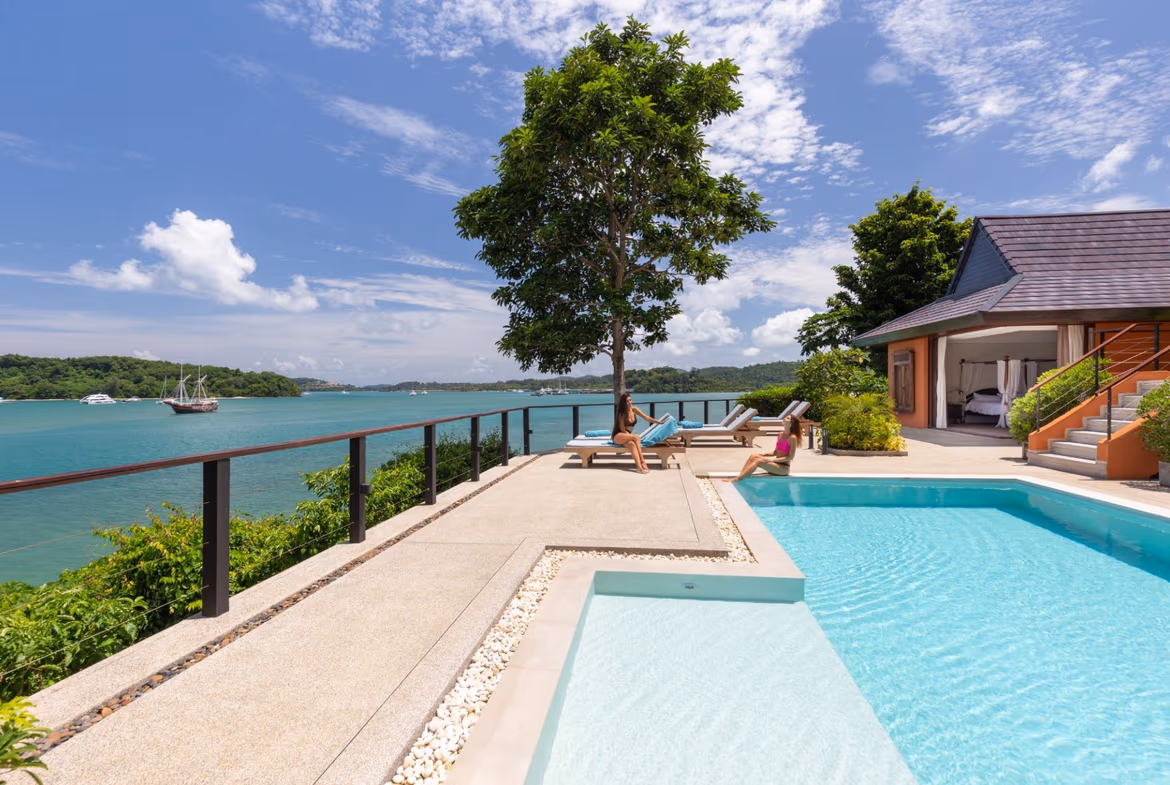 A five-bedroom villa in Ao Yon, featuring an oceanfront infinity pool and multiple balconies. The white exterior contrasts with the blue ocean and sky.