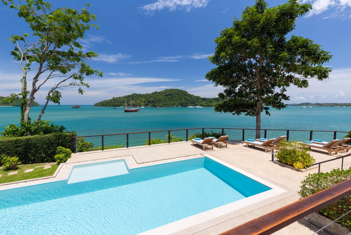 An elevated long shot captures a private infinity pool overlooking the ocean at sunset.