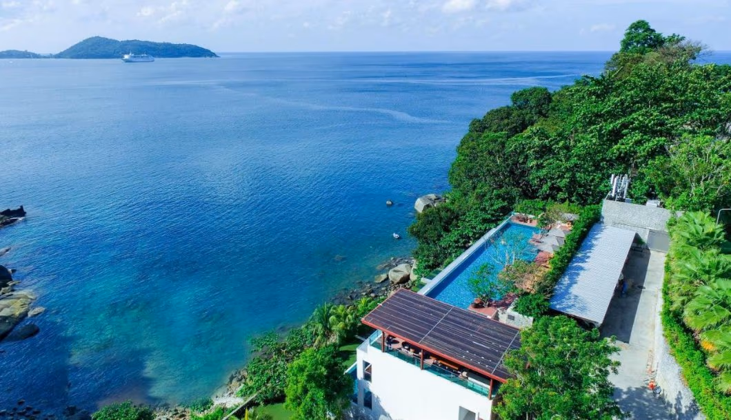 A view of the ocean from a balcony or terrace furnished with a table and chairs.