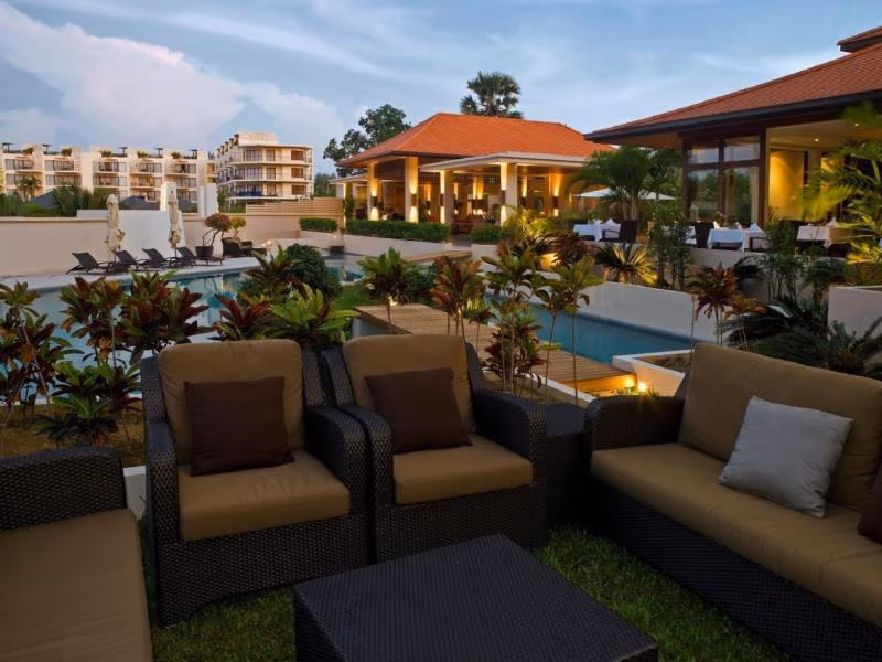 A modern hotel guestroom with a bed, desk, and sliding door opening to a private balcony.