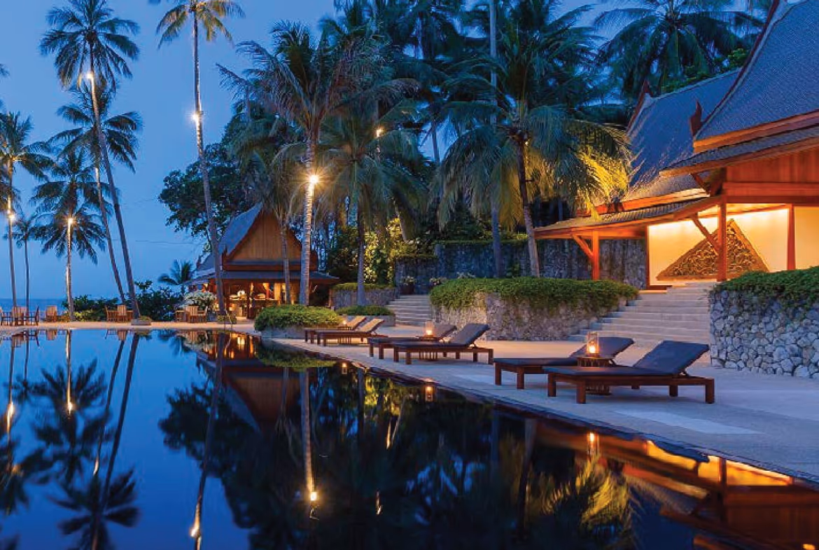 A spacious living area with traditional Thai decor and view of a private pool, suggesting a single-family villa.