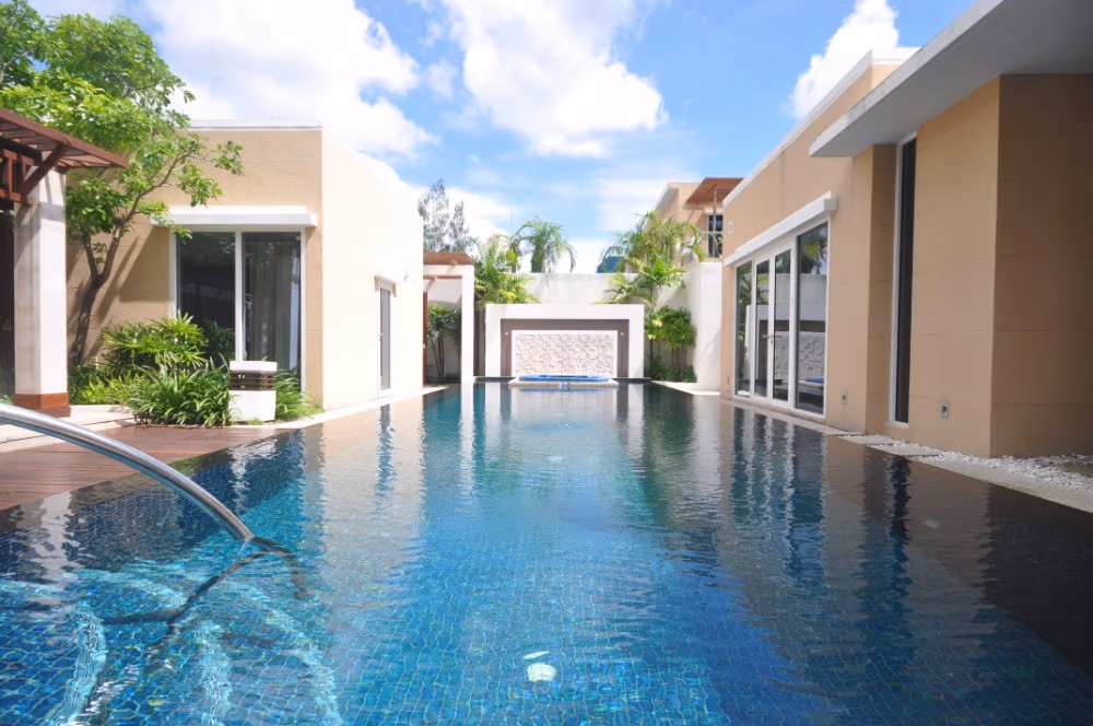 A bedroom with a king-sized bed facing glass doors that open to a private swimming pool and a view of the ocean.