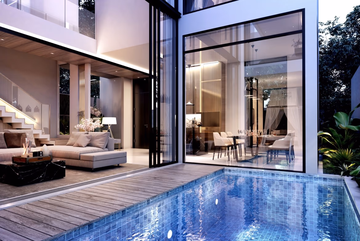 A modern living room with a large sofa and television, overlooking a private swimming pool through a glass wall.
