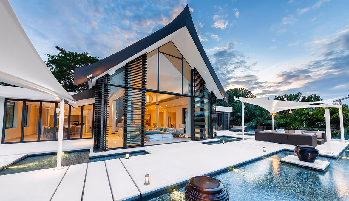 A spacious living area with large windows opens onto an outdoor patio overlooking the ocean.