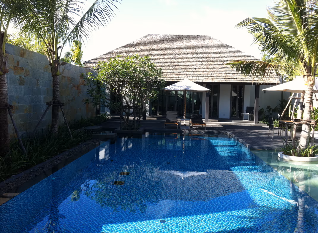 A view of the outdoor swimming pool surrounded by a deck and some lounge chairs.