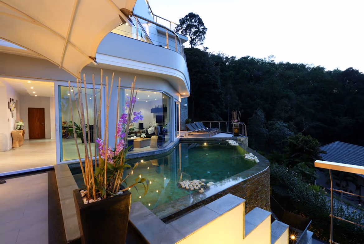 The photo shows an outdoor swimming pool with lounge chairs and a view of the ocean.