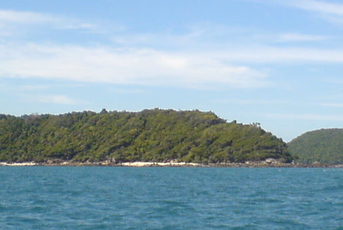 A panoramic aerial view of a private island with lush greenery, beaches, and surrounding clear blue water.