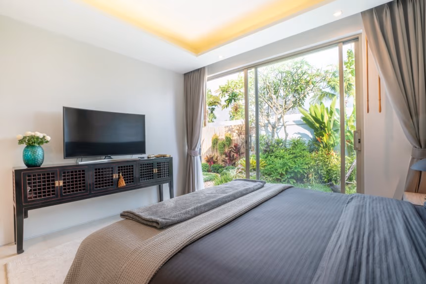 A corner of a modern living room with a large, comfortable sofa and a coffee table, overlooking an outdoor patio.