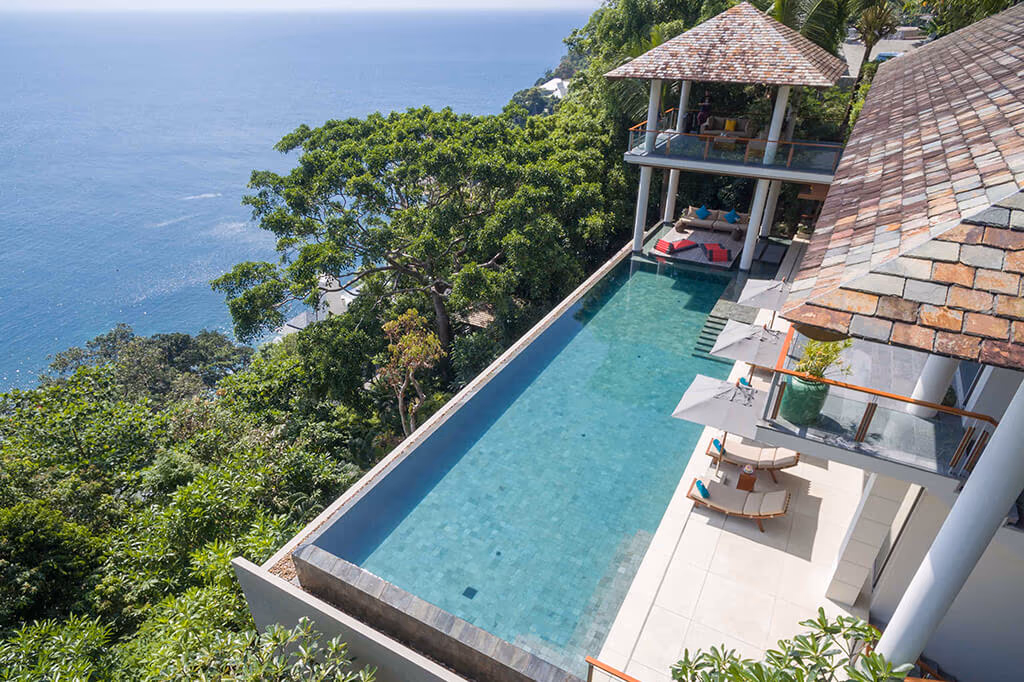 A view of the ocean from a balcony or patio, with hills visible in the distance.