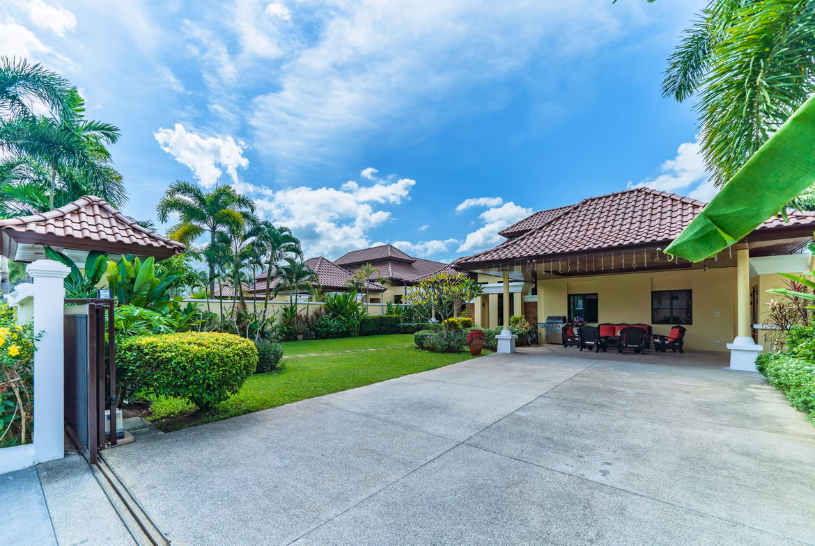 A modern, spacious living room with large windows and a view of the pool.