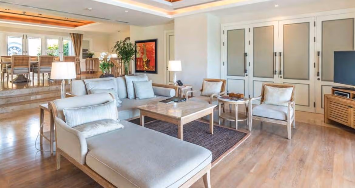 A spacious living room with modern furnishings and large windows overlooks the ocean.