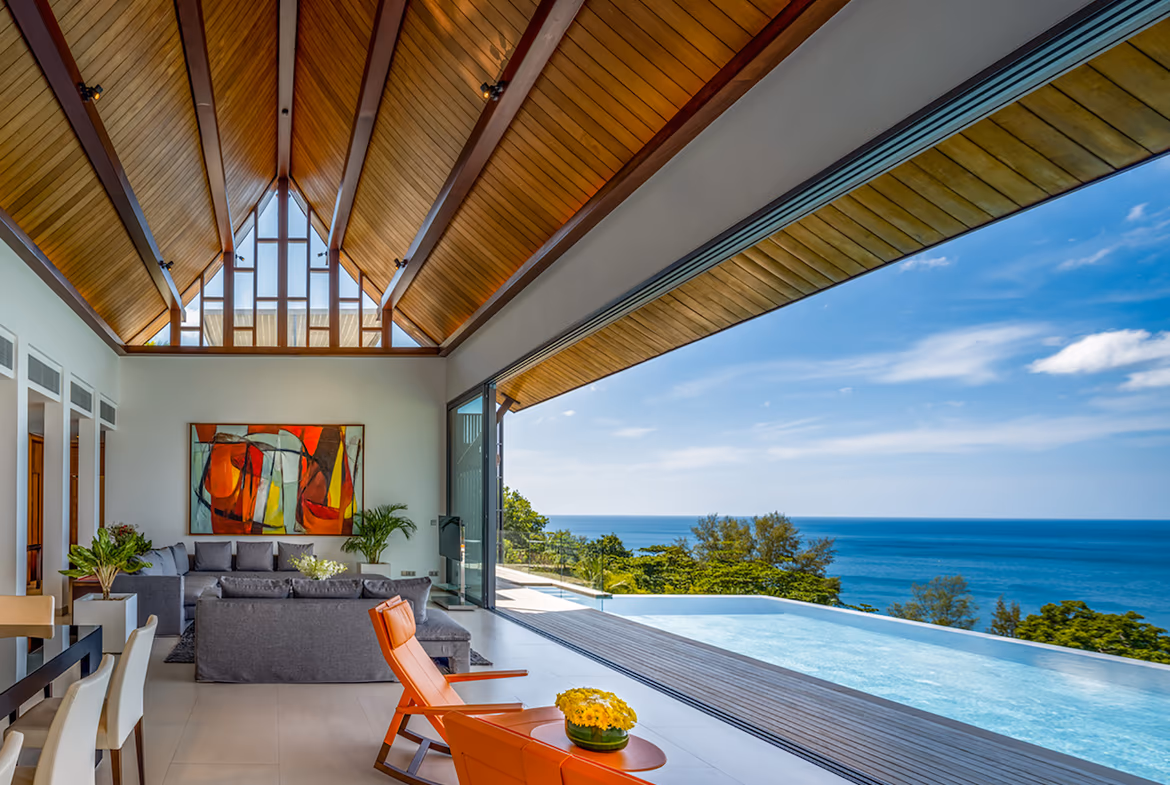 A luxurious infinity pool overlooking the Andaman Sea with sun loungers and a modern outdoor seating area.