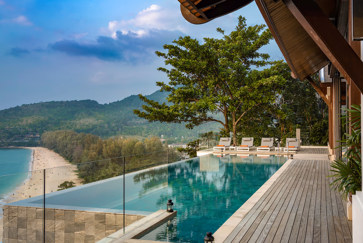 A spacious living room opens to an outdoor patio with a swimming pool and distant ocean views.
