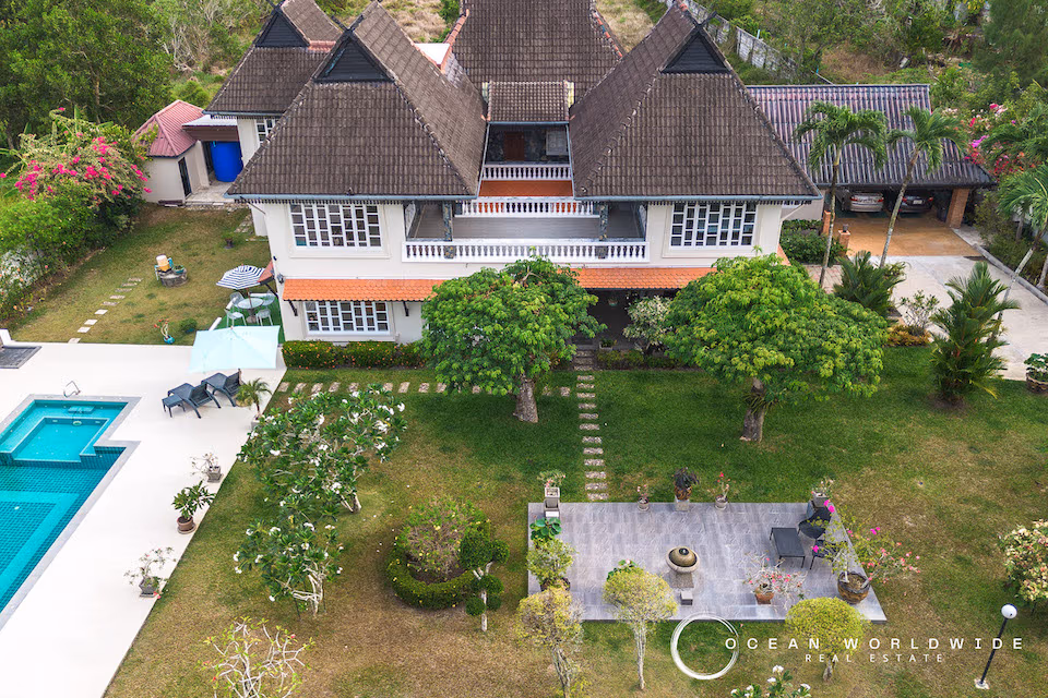 A spacious living room with traditional decor and large windows looking out onto a lush garden.