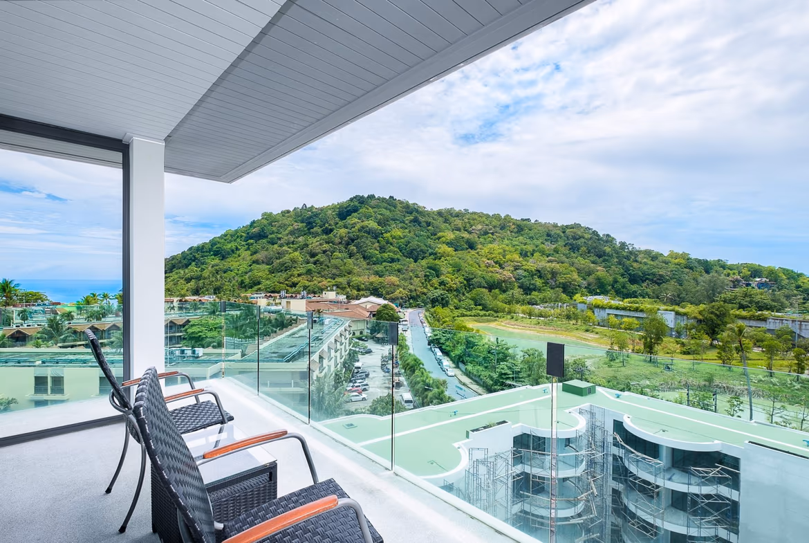 A modern condominium building with large windows and balconies overlooks the Patong coastline. This two-bedroom unit offers sea views from its elevated position.