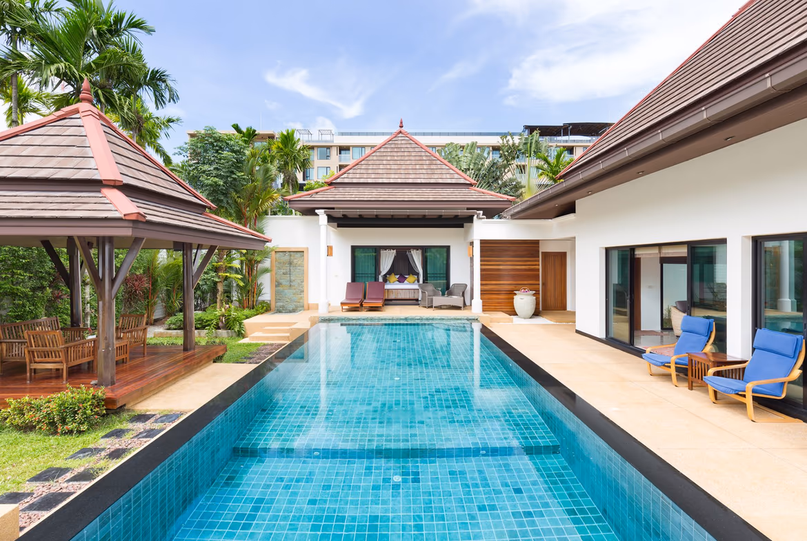 An outdoor swimming pool surrounded by a patio with lounge chairs.