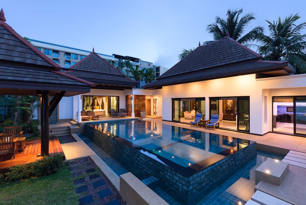 An outdoor swimming pool with surrounding lounge chairs and lush tropical landscaping.