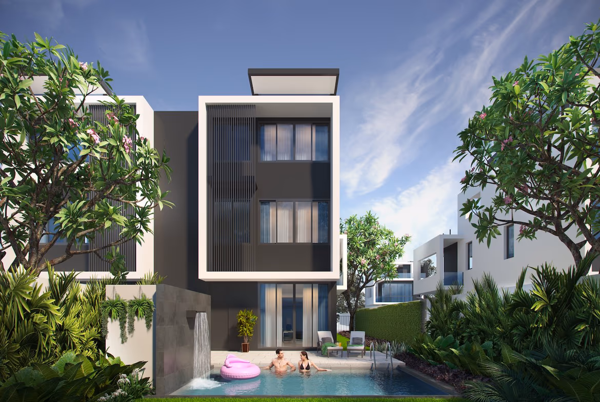 A contemporary villa under a clear sky in Bang Tao. It features multiple stories with wide windows and balconies, overlooking lush green landscaping.
