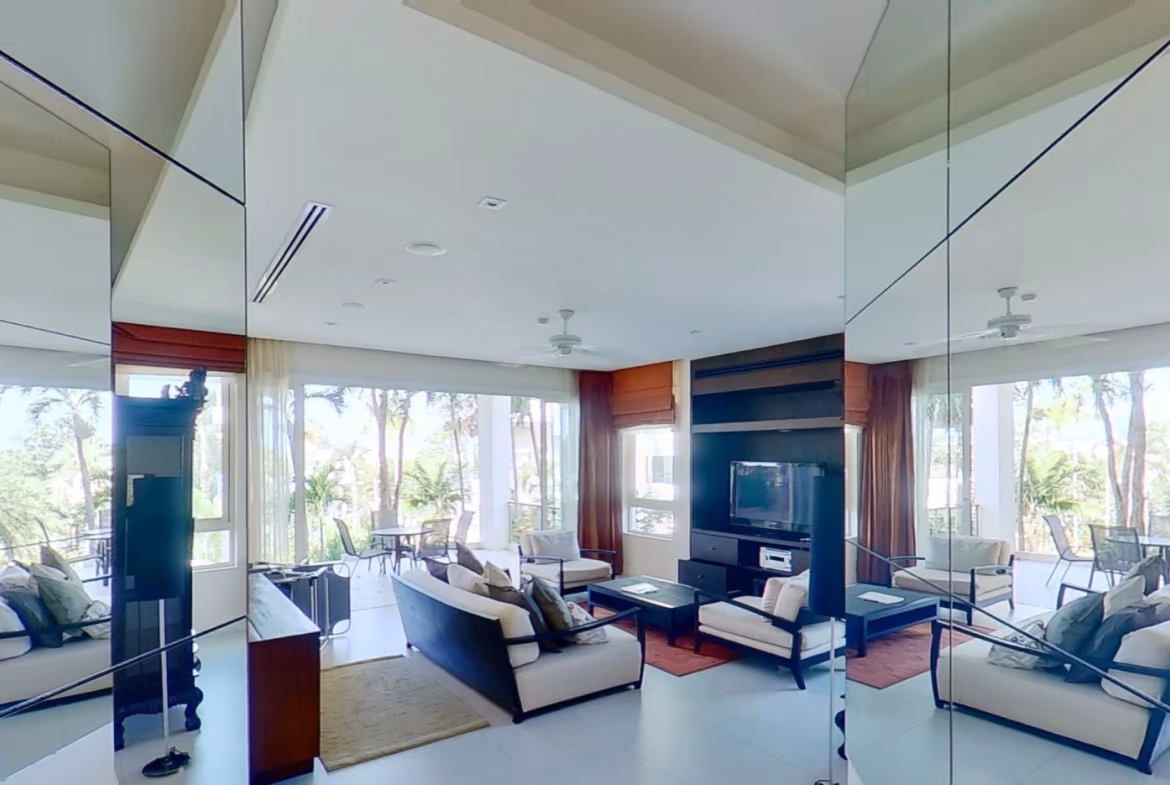 A well-lit bedroom with a large window overlooking a tropical landscape.