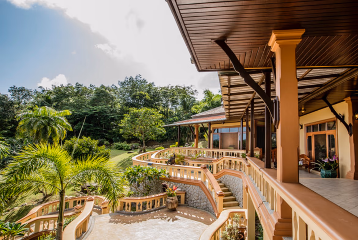 A spacious living room featuring a large sectional sofa, a coffee table, and a view of a tropical garden.