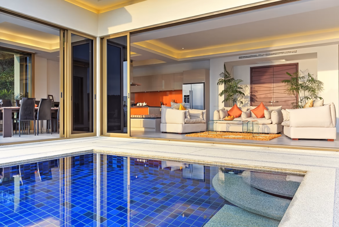 This image shows a bedroom with a large window looking out onto a private swimming pool and distant ocean.