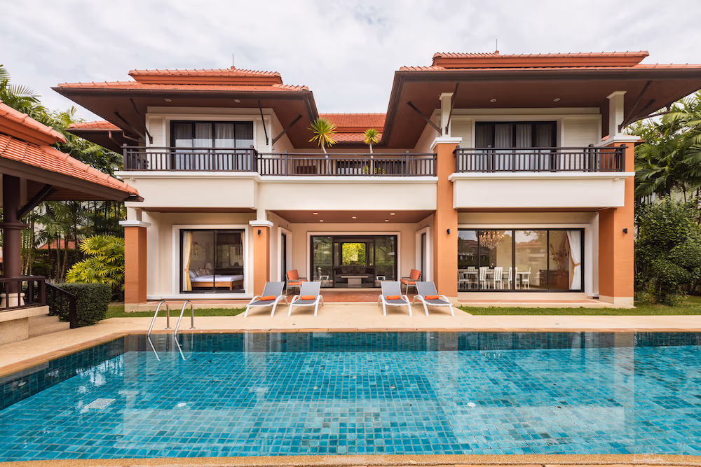 This image displays an outdoor swimming pool overlooking a serene lake and lush greenery.