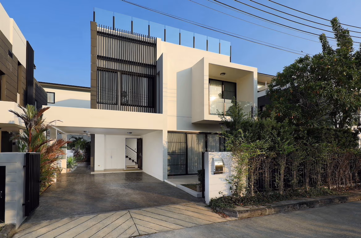 Four-bedroom villa in Bang Tao with a modern, flat-roofed design. The exterior features light-colored walls and large windows, surrounded by tropical foliage.