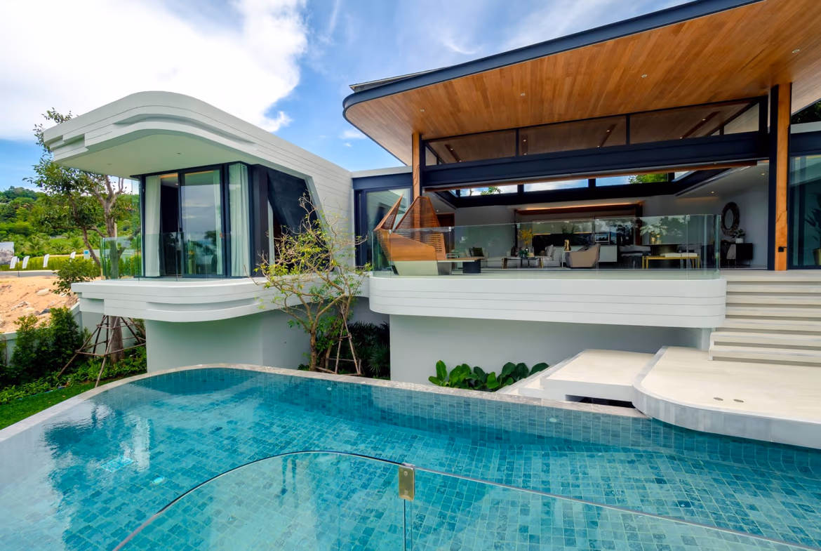 This image shows a modern outdoor patio with loungers and an infinity pool overlooking a tropical landscape.