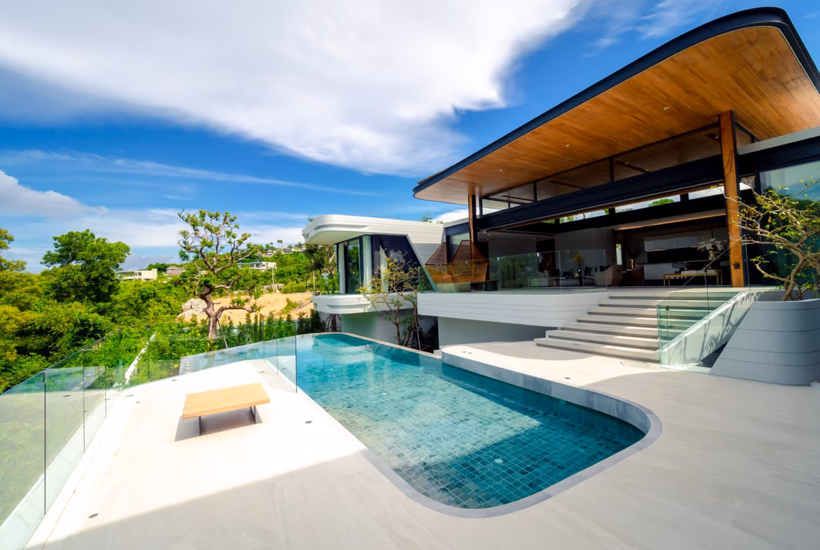 A spacious, modern living area with large glass doors opening to an outdoor patio and pool.